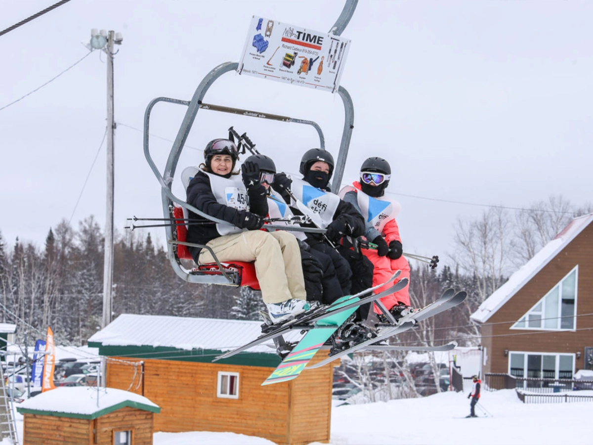 Des skieurs prennent la pose dans un télésiège lors du Défi Ski Leucan