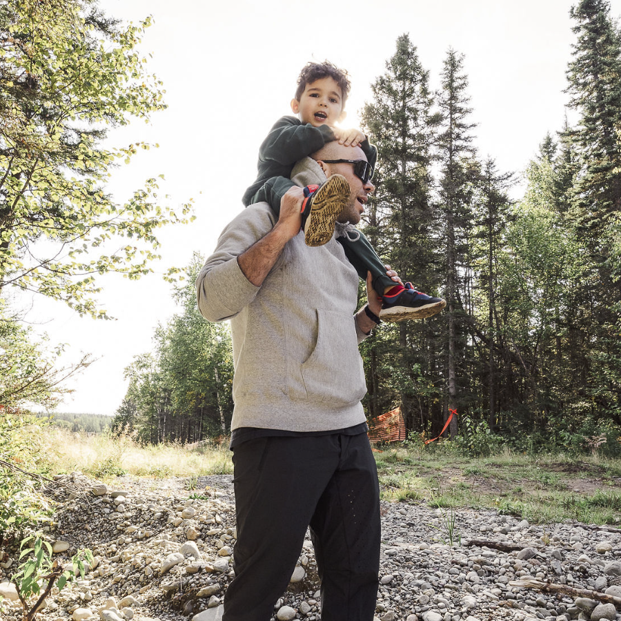 Un père qui porte son fils sur les épaules mache en sentier